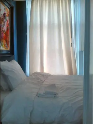 a bed in front of a window with white curtains at Miss Jordaan for Quiet Travellers in Amsterdam