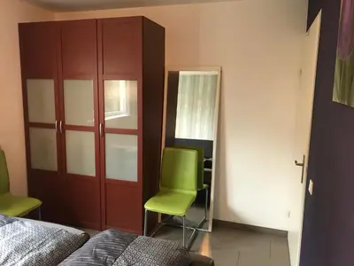 a bedroom with a green chair and a mirror at Fewo Klimduin Castricum in Castricum