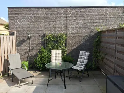 a patio with a table and two chairs and a brick wall at Fewo Klimduin Castricum in Castricum