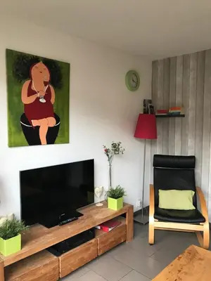 a living room with a flat screen tv and a chair at Fewo Klimduin Castricum in Castricum