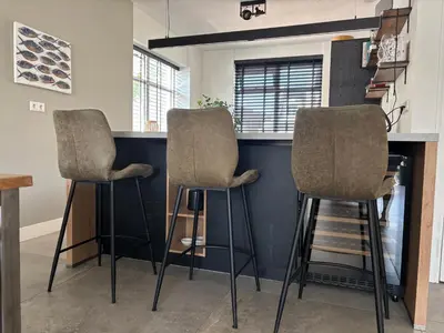 a kitchen with two bar stools at a counter at Wellness Villa Binnenhof in Noordwijk