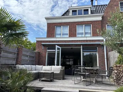 a brick house with a couch and chairs on a patio at Wellness Villa Binnenhof in Noordwijk