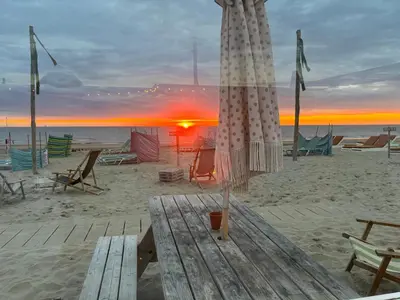 a beach with chairs and an umbrella on the sand at Wellness Villa Binnenhof in Noordwijk