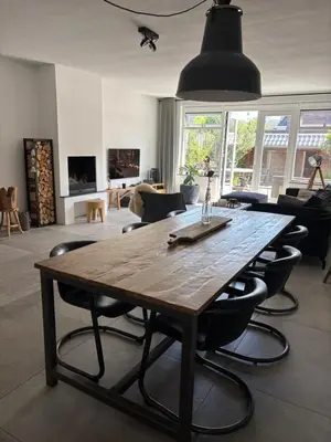 a large wooden table in a living room with chairs at Wellness Villa Binnenhof in Noordwijk