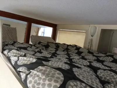 a bed with a black and white comforter in a bedroom at Cosy Studio, with outdoor swimming in Amsterdam