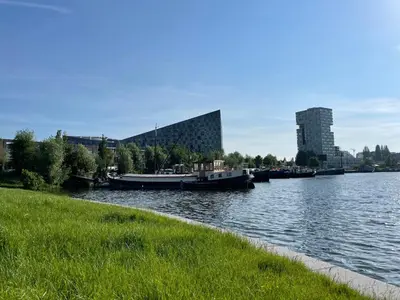 a couple of boats docked on a river with a building at Cosy Studio, with outdoor swimming in Amsterdam