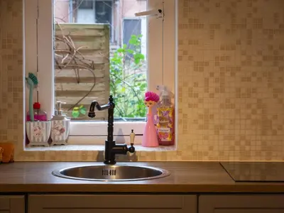 a kitchen sink with a faucet next to a window at Garden Apartment, Amsterdam in Amsterdam