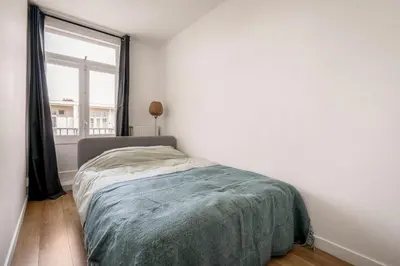 a bedroom with a bed and a large window at Light and quiet haven next to park in Amsterdam