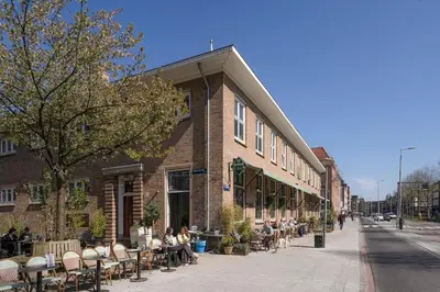 people sitting in chairs outside of a brick building at Light and quiet haven next to park in Amsterdam