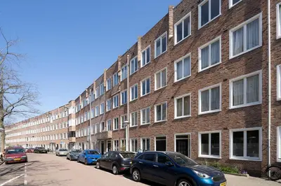 a large brick building with cars parked in front of it at Light and quiet haven next to park in Amsterdam