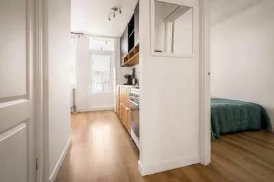 a kitchen with white walls and a wooden floor at Light and quiet haven next to park in Amsterdam