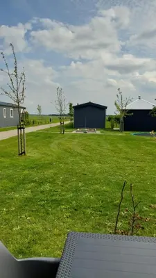 a view of a field of grass with a building at Recreatie aan de Vecht, Hooibergje 2, Weesp in Weesp