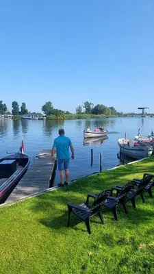 a man standing at a dock with boats in the water at Recreatie aan de Vecht, chalet 3, genieten van de rust en ruimte en toch dichtbij de stad in Weesp