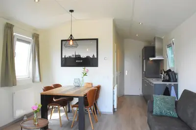 a dining room and living room with a table and chairs at Recreatie aan de Vecht, chalet 3, genieten van de rust en ruimte en toch dichtbij de stad in Weesp