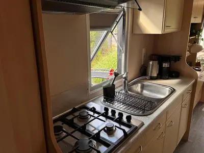 a kitchen with a stove and a sink and a window at Vlinderzicht in Koedijk