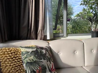 a white couch with a pillow in front of a window at Vlinderzicht in Koedijk