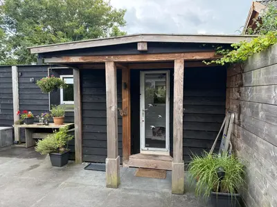 a wooden shed with a door on a patio at Vlinderzicht in Koedijk