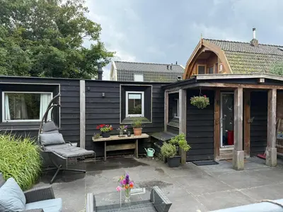 a black tiny house with a patio and a table at Vlinderzicht in Koedijk