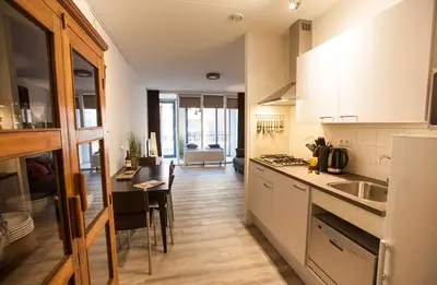 a kitchen with white cabinets and a table and a counter at Apartment 4G in Amersfoort