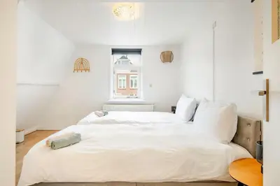 a white bedroom with a large white bed at Large Family House Alkmaar in Alkmaar