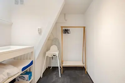 a room with a staircase with a chair and a mirror at Large Family House Alkmaar in Alkmaar