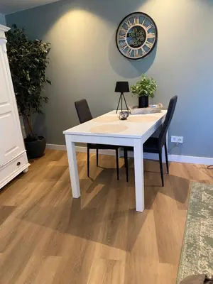 a white table with two chairs and a clock on the wall at Costa C en E in Noordwijk