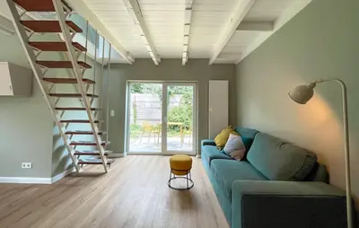 a living room with a blue couch and a staircase at Cozy Home In Bergen Aan Zee With Wifi in Bergen aan Zee