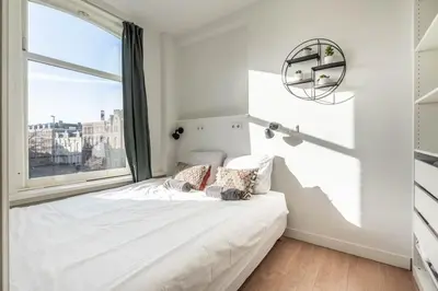 a bedroom with a bed with a large window at Panoramic canalview apartment in Amsterdam