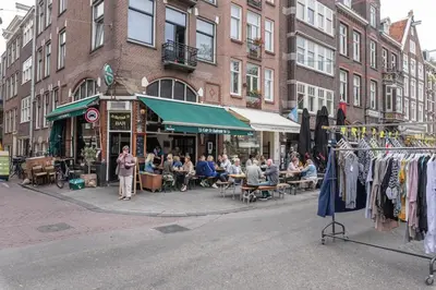 a group of people sitting outside a store on a city street at Panoramic canalview apartment in Amsterdam