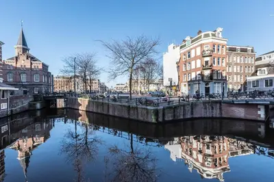 a river in a city with buildings and a bridge at Panoramic canalview apartment in Amsterdam