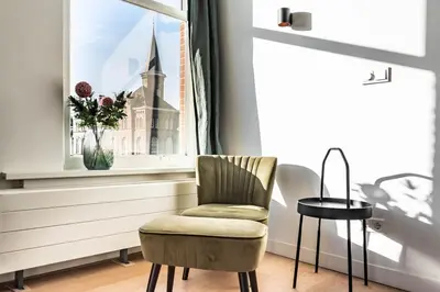 a chair in front of a window with a church at Panoramic canalview apartment in Amsterdam