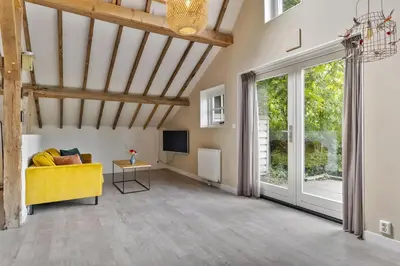 a living room with a yellow couch and a tv at Boerderijwoning 't Trogje in Heiloo