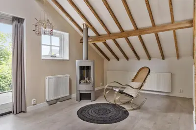 a living room with a chair and a fireplace at Boerderijwoning 't Trogje in Heiloo