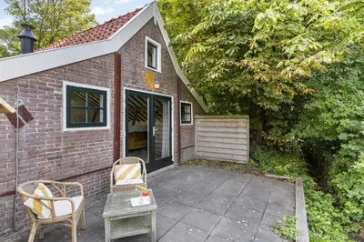 a brick house with two chairs and a table at Boerderijwoning 't Trogje in Heiloo