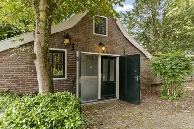 a brick house with a green door and a tree at Boerderijwoning 't Trogje in Heiloo