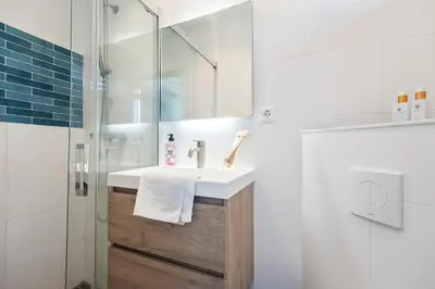 a white bathroom with a sink and a shower at De Schelp 66, Free parking in Zandvoort