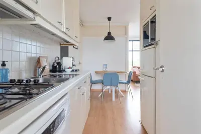 a kitchen with white cabinets and a table with chairs at De Schelp 66, Free parking in Zandvoort