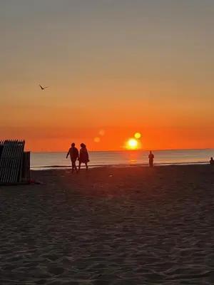 a group of people walking on the beach at sunset at Sonne in Egmond aan Zee