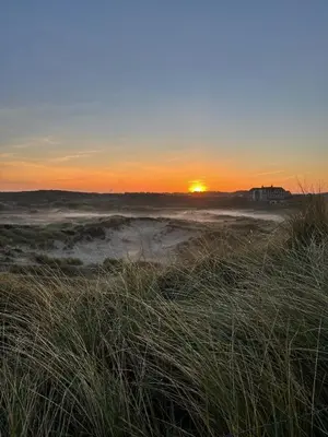 a sunset on a beach with the sun in the background at Sonne in Egmond aan Zee