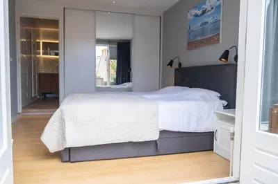 a bedroom with a large white bed and a mirror at T Pronkhuis in Egmond aan Zee