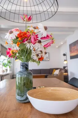 a vase with flowers in it sitting on a table at T Pronkhuis in Egmond aan Zee