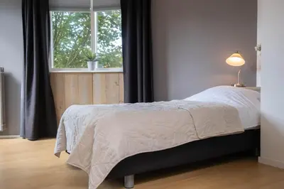 a bedroom with a large bed with a window at T Pronkhuis in Egmond aan Zee