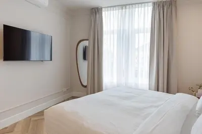 a white bedroom with a bed and a large window at Boutique hotel Novi in Zandvoort