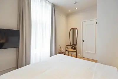 a bedroom with a bed and a chair and a window at Boutique hotel Novi in Zandvoort