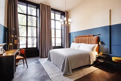 a bedroom with blue walls and a bed and a desk at The Hoxton, Amsterdam in Amsterdam