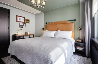 a bedroom with a large bed and a chandelier at The Hoxton, Amsterdam in Amsterdam