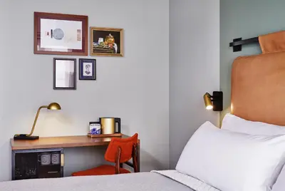 a hotel room with a bed and a desk with a bed and a chair at The Hoxton, Amsterdam in Amsterdam