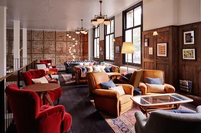 a waiting room with chairs and tables and windows at The Hoxton, Amsterdam in Amsterdam