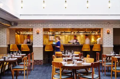 a restaurant with tables and people in the kitchen at The Hoxton, Amsterdam in Amsterdam