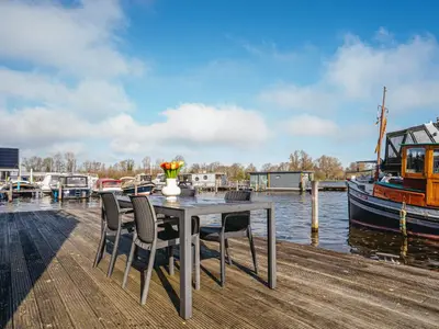 a table and chairs on a dock with a boat at Apartment Westergeest 2 by Interhome in Uitgeest